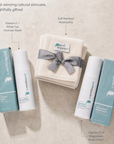 A styled flat-lay of Pod Organics natural skincare products on a light beige textured background, featuring two boxed intimate washes, one body creams, a folded washcloth bundle tied with a gray ribbon, and descriptive text callouts.