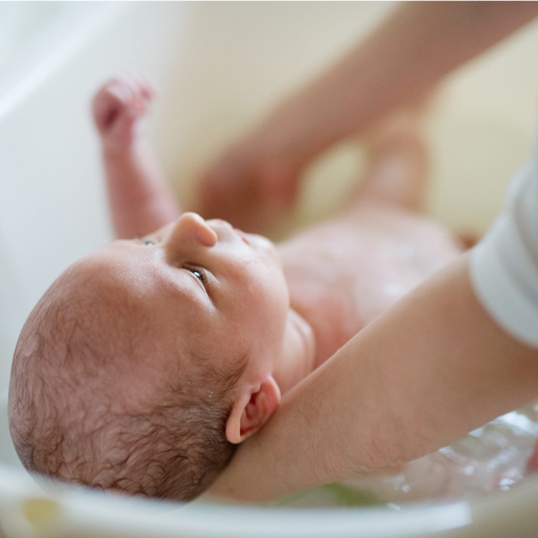 Newborn baby being bathed with a baby bath & massage oil