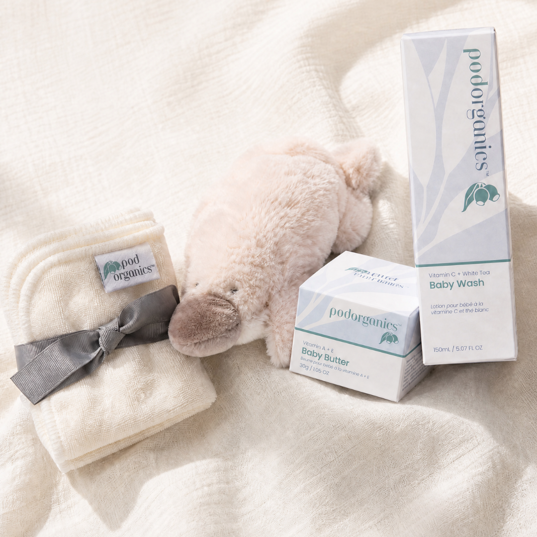 Pod Organics The First Weeks Set with baby wash, baby butter, bamboo wash cloths and Puddles the plush platypus on a white background
