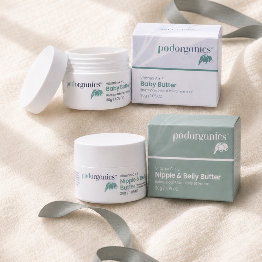 Pod Organics Nipple Cream &amp; Belly Butter and Vitamin A+E Baby Butter jars with their boxes on beige fabric